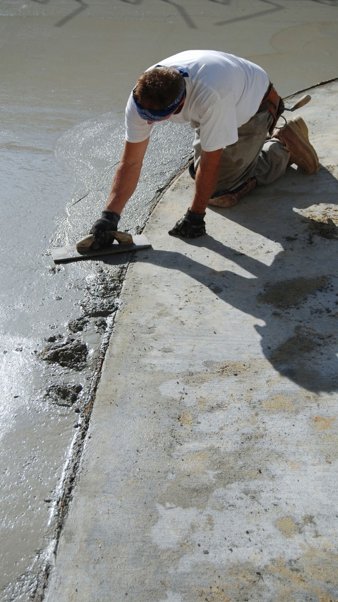 Construction worker smoothing freshly poured concrete, demonstrating quality craftsmanship and attention to detail in concrete work.